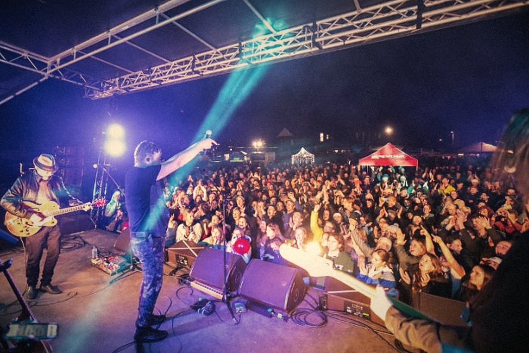 Dragon performing to a packed outdoor crowd in Methven, seen from side of stage